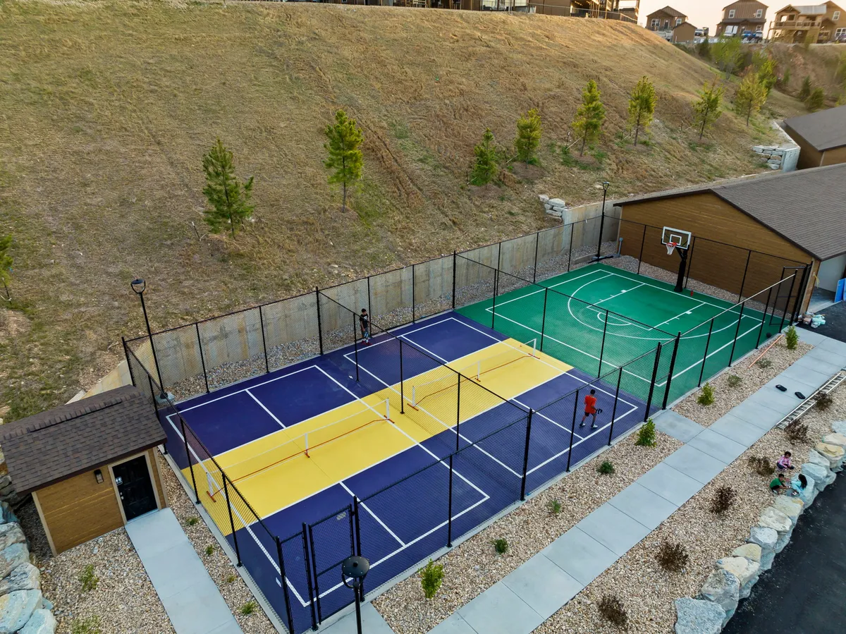 A lively shot of well-maintained courts, including both tennis/pickleball and basketball areas, set against a backdrop of green hills. The courts are ready for action, inviting guests to get active and engage in friendly matches or tournaments.