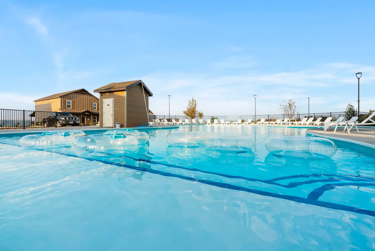 A vibrant outdoor swimming pool scene with floating tubes, a shaded cabana, and inviting lounge chairs. The mood is leisurely, suggesting both relaxation and social fun. The pool is a hub of activity, ideal for both families and groups.